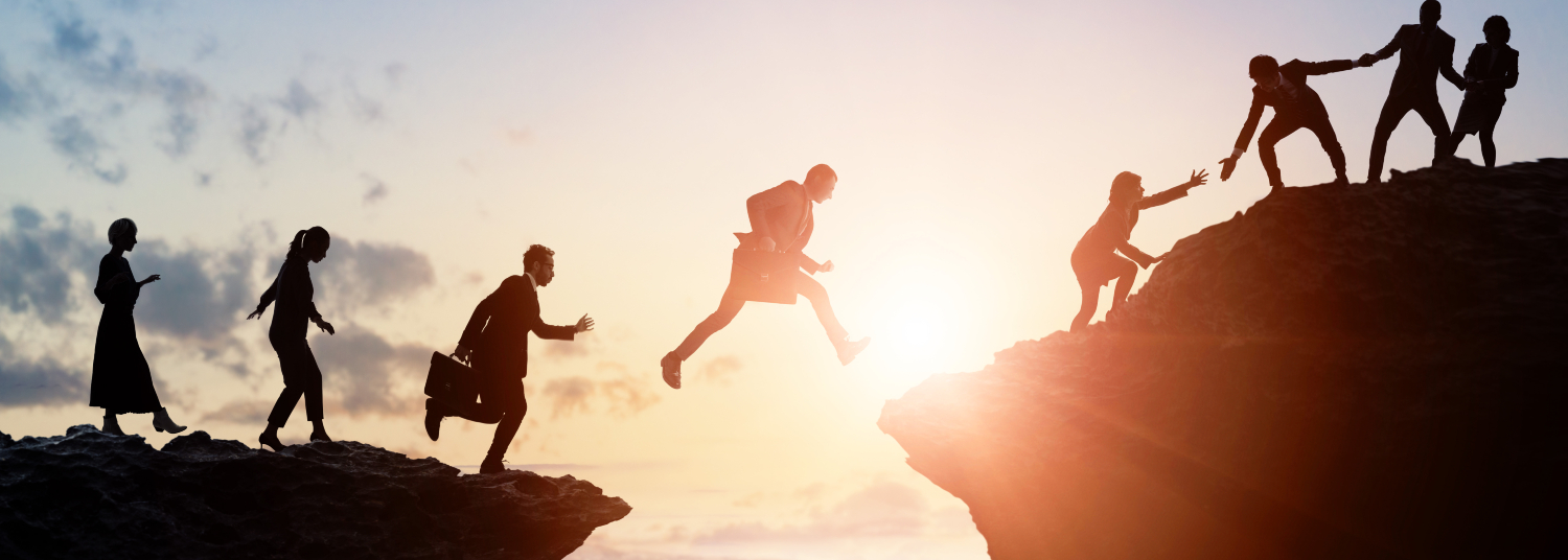 Businesspeople jumping together safely from one cliff to another