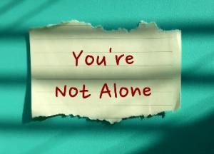 You're Not Alone handwritten message taped to wall